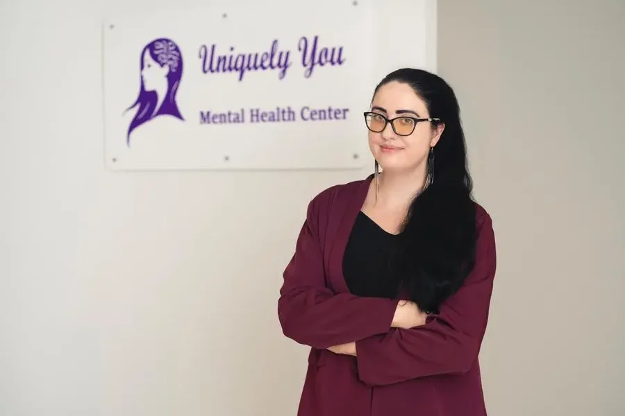 Elaine Maichin, founder of Uniquely You Mental Health Center, standing in front of her clinic's sign.