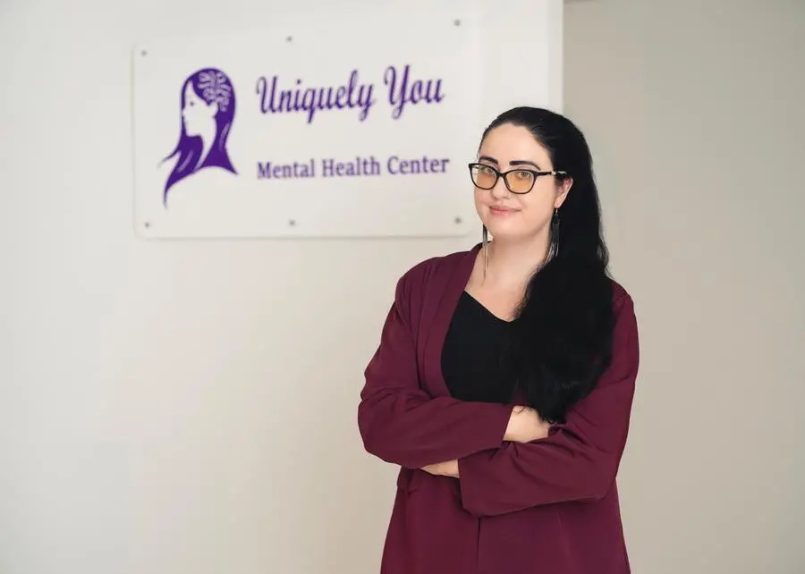 Elaine Maichin, founder of Uniquely You Mental Health Center, standing in front of her clinic's sign.